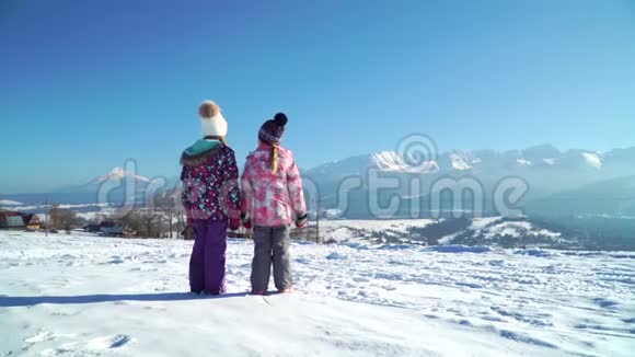 雪中儿童站在乡间小路上阳光下看山脉视频的预览图
