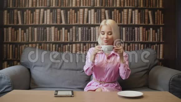 在咖啡馆里喝咖啡和看书的金发女人视频的预览图