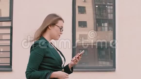 在户外戴眼镜走路和使用数字设备时微笑女商人视频的预览图