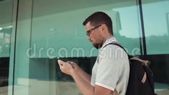 男游客正在散步看着他的手机展示视频的预览图