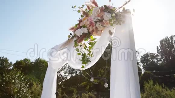 在阳光明媚的夏日婚礼拱门装饰着鲜花节日花装饰玫瑰和羽毛草视频的预览图