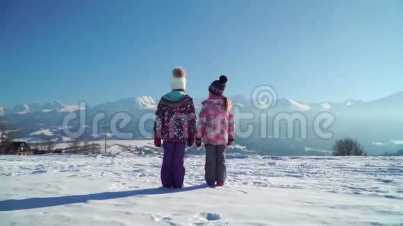 雪中儿童站在乡间小路上阳光下看山脉视频的预览图