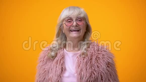 可爱的老太太穿着滑稽的粉红色衣服做着摇臂的姿势积极的视频的预览图