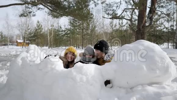 妈妈儿子和爸爸躲在雪墙后面扔雪球视频的预览图