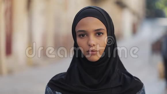 女人抗拒象征年轻的穆斯林妇女戴着头巾站在老街上做拳头手势视频的预览图