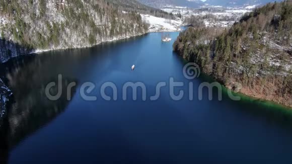 一艘船在蓝水的山湖上航行的空中镜头4k视频的预览图