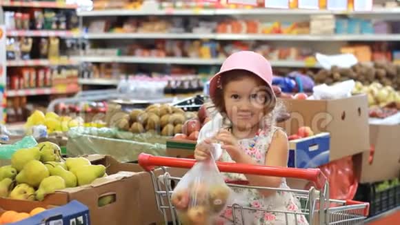 商店里的小女孩选择水果梨杂货店和购物车视频的预览图