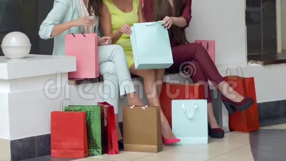 购物者的生活方式女孩们在旺季逛完时尚商店后考虑在腿边的纸袋里购物视频的预览图