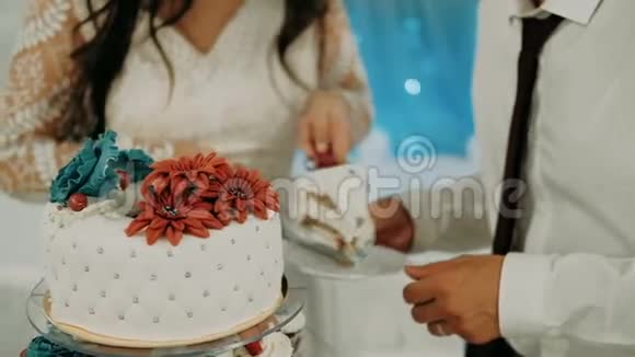 新娘和新郎用有趣的装饰切结婚蛋糕视频的预览图