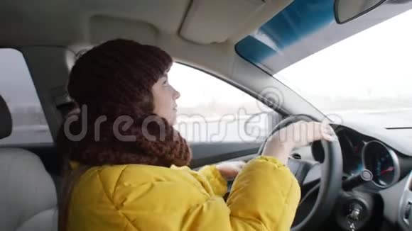 一位穿着黄色夹克的年轻女子坐在司机座位上放下面罩看着镜子整理头发视频的预览图