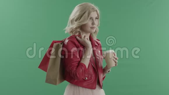 女人喝着咖啡手里拿着手表放在绿色屏幕上的袋子视频的预览图