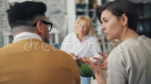 女性治疗师在夫妻关系咨询期间与不幸的夫妻交谈视频的预览图