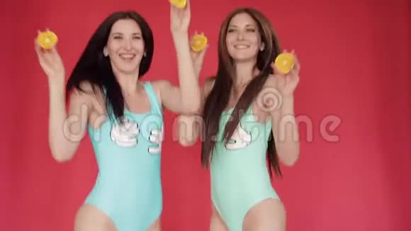 快乐的姐妹们涉猎玩橘子鲜艳的宣传视频带橘子的红色背景上的布吕尼视频的预览图