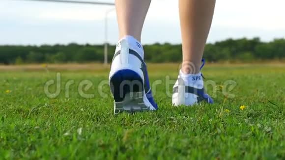 一个长着美丽纤细腿的女孩走在绿色的田野上女足穿运动鞋特写体育和户外活动视频的预览图