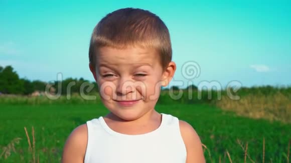 4岁的男孩穿着一件白色的t恤害羞地对着镜头微笑然后移开目光一个小可爱的孩子的肖像视频的预览图