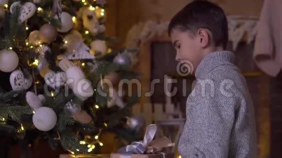 小男孩在圣诞树附近放了一个带礼物的盒子高清高清视频的预览图