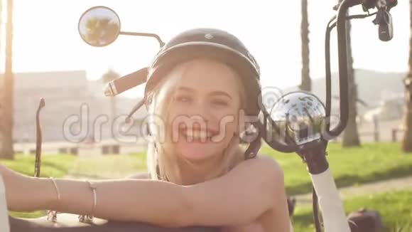 戴着头盔和防护眼镜的年轻女孩坐在电动自行车旁边视频的预览图