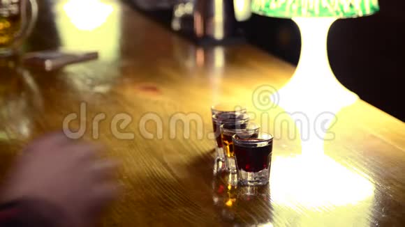 朋友在夜总会喝酒喝酒酒吧柜台上的男性双手拿着带酒精饮料的小眼镜视频的预览图