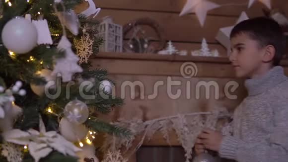 一个小男孩装饰一棵圣诞树一个漂亮的球心情很好高清高清视频的预览图
