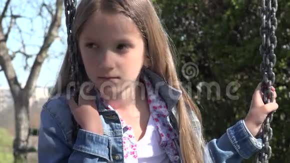 摇摆中的悲伤的攻击性儿童孤独的女孩在户外玩耍忧郁的孩子视频的预览图