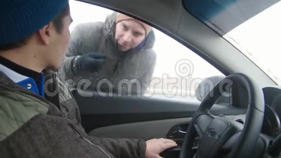 年轻人坐在驾驶座上他的朋友来到窗前那人放下窗户向他的朋友打招呼视频的预览图