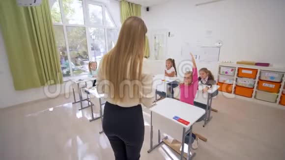 在学校的课堂教学中女教育家和可爱的小学者在课桌旁交谈视频的预览图