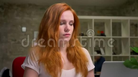 放松的浓白白种人姜女正在电脑上打字坐在室内桌面上富有创意的现代视频的预览图
