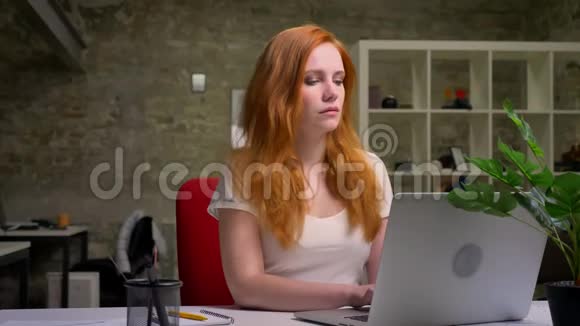 美丽的白种人女性坐在笔记本电脑上打字姜发工作氛围室内光线办公室视频的预览图