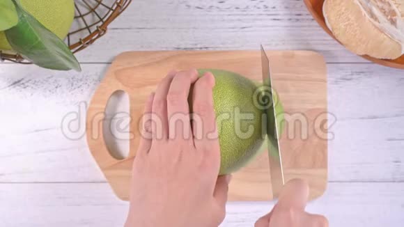 年轻的亚洲妇女切去新鲜蜜柚在明亮的白色木桌和砧板上吃厨房俯视俯视视频的预览图