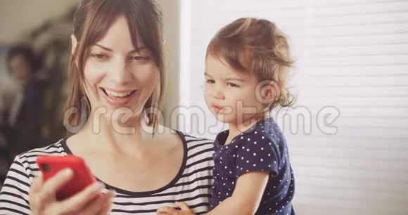 快乐的妈妈和宝贝女孩在智能手机上进行视频聊天视频的预览图