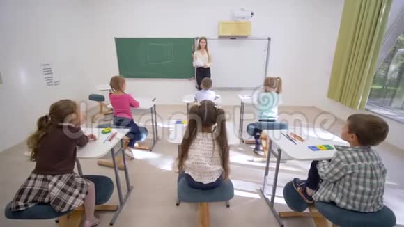 一群小学生在上课时举手回答问题坐在教师面前的课桌前上小学视频的预览图