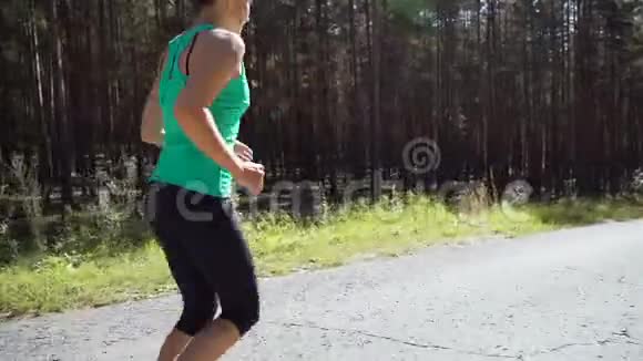 美丽的白种人女运动员在松林的柏油路上度过了阳光明媚的夏日健康的生活方式观念视频的预览图