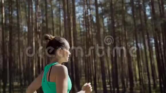 美丽的白种人女运动员在松林的柏油路上度过了阳光明媚的夏日健康生活方式视频的预览图