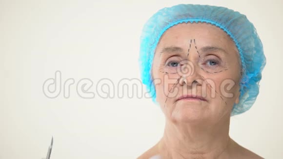 外科医生将手术刀放置在有痕迹的老年女性患者面部面部抬起视频的预览图