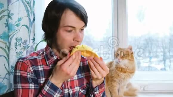 白种人和红猫在家里的厨房里一起吃芒果视频的预览图