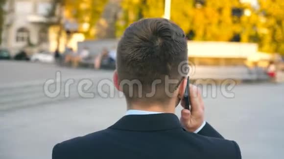 镜头旋转的英俊商人在电话户外戴太阳镜的年轻商人视频的预览图