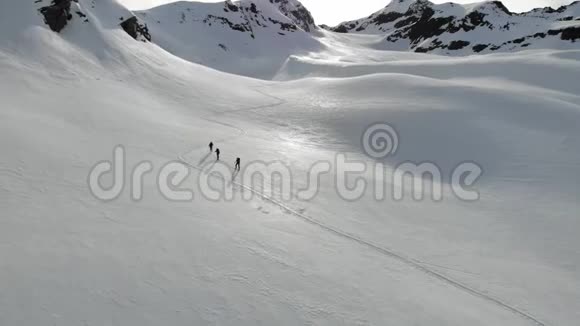 空中无人驾驶飞机射击直线山和滑雪者步行上山与滑雪和杆支持视频的预览图