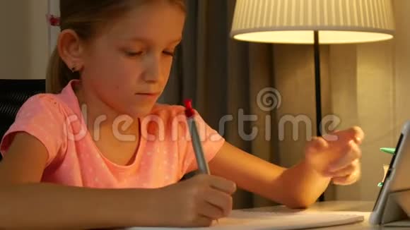 儿童使用平板电脑学习女孩写作业夜间上网使用4K视频的预览图