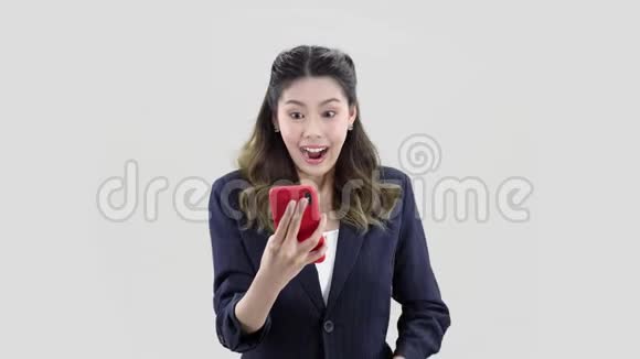 年轻的美女穿着深色条纹夹克手里拿着红色手机开心地笑着视频的预览图