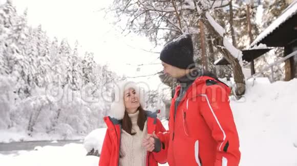 一对年轻夫妇在冬天的风景和有趣的谈话中走在一条山河附近视频的预览图