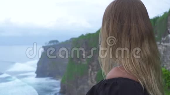 游女在悬崖山上海浪背景在海洋海岸年轻的观光客正在观看悬崖山视频的预览图
