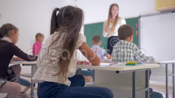 小学课堂课上微笑女生在课桌上的画像视频的预览图