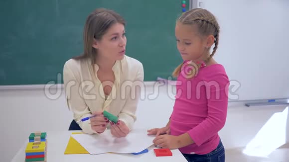 孩子们的教育年轻的导师用塑料数字教聪明的女学生在桌子附近的教室视频的预览图