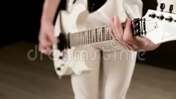 特写时尚的节奏吉他手不同的眼睛穿着白色衣服黑色背景富有表现力地演奏视频的预览图