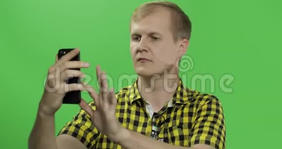 穿黄色衬衫的白人年轻人用手机进行视频通话视频的预览图
