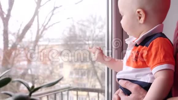 靠近一个小男孩他和他的老爷爷在窗前的一棵树的背景下玩耍视频的预览图