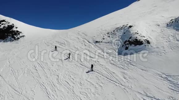 空中无人驾驶飞机射击高山和滑雪者在山上行走并提供滑雪和支撑杆视频的预览图