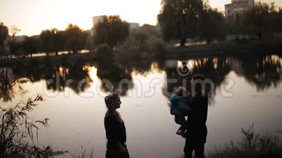 欢乐的一家人在秋天公园的湖底剪影视频的预览图