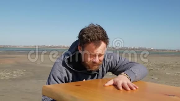 一个长着胡子胡子的蓝眼睛木匠用手摸着桌子的表面视频的预览图