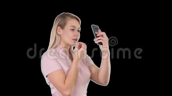 美女人化妆年轻女人嘴唇看着智能手机阿尔法频道视频的预览图